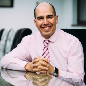 Adam Boddison is sat at a desk smiling